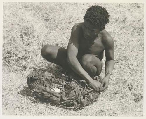 ≠Toma lining a carrying net with a small kaross to pack it with rattles, ostrich eggshells, etc.
























