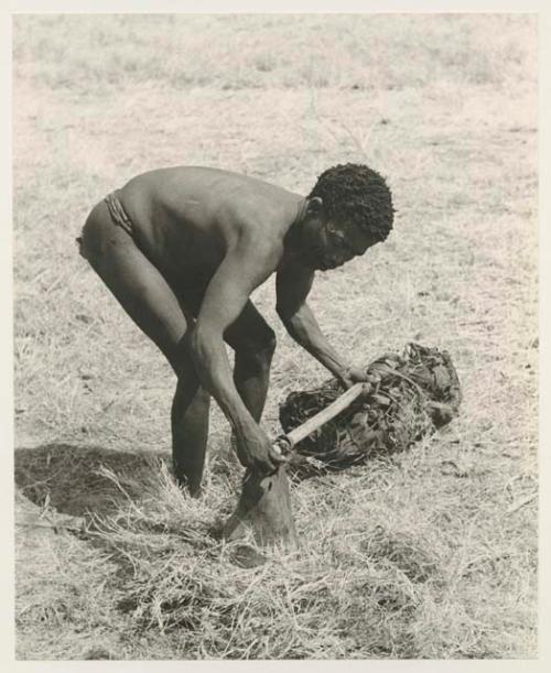 ≠Toma bending over to put a net and a bag on a carrying stick
























