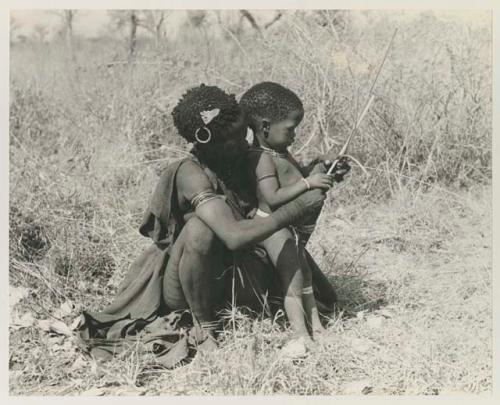 Di!ai showing her son Debe how to make an arrow






















