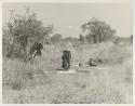 Ju/'hoansi sitting in grass, distant view
