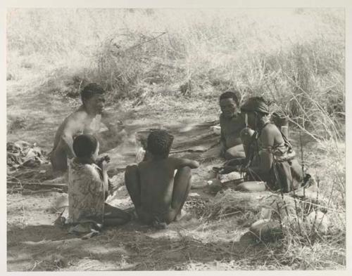 "Old Gau" to the left, two unidentified Ju/'hoan boys, Di!ai, and Gao, father of N!aba, all seated
