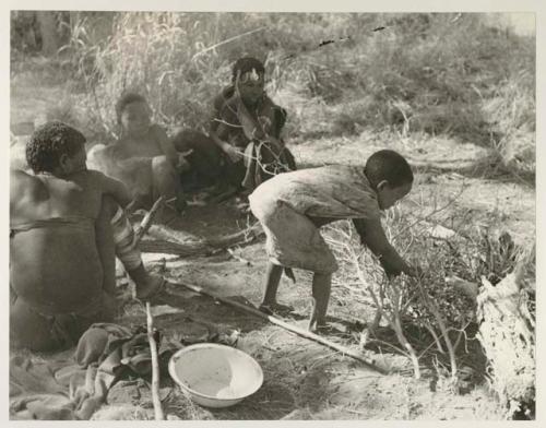 "Little ≠Gao" in a scarf leaning over with other unidentified people, seated
