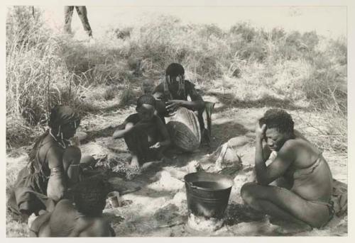 "Old Gau" beside the bucket and unidentified people, all seated