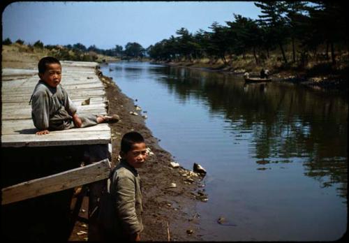 Two boys near dock along canal