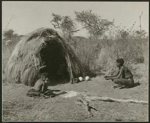 "N!ai and /Gunda": Little N!ai" and /Gunda (son of Khwan//a and her former husband) sitting by their skerm, with children playing in the skerm and their possessions outside the skerm (print is a cropped image)