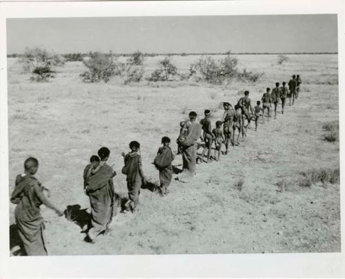 "Band moving": Band of people walking in a line, with the men in the front and the women in the back