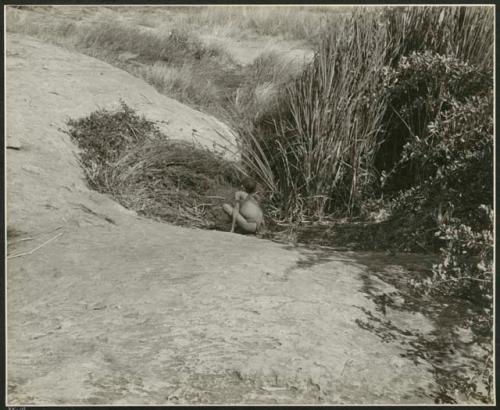 "Waterhole / Gwia": Boy crouching beside the Gautscha waterhole