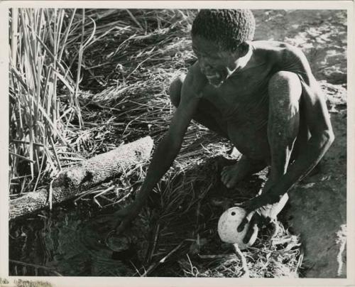 "Waterhole / Gwia": "Old /Gaishay" of Band 4 filling his ostrich eggshell with water (print is a cropped image)