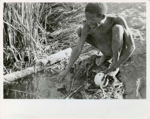 "Waterhole / Gwia": "Old /Gaishay" of Band 4 filling his ostrich eggshell with water (print is a cropped image)