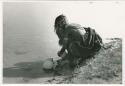 "Waterhole / Gwia": Girl filling an ostrich eggshell, seen from behind (print is a cropped image)