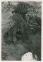 [No folder title]: Woman sitting and playing a dandiri, seen from behind (print is a cropped image)