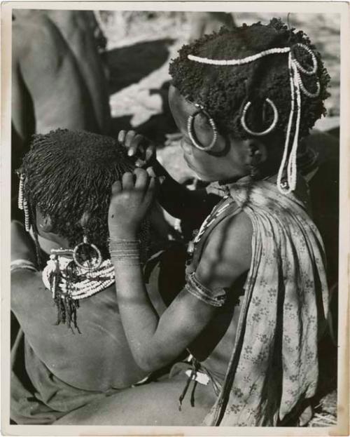 "Grooming & haircuts": Girl looking for lice in the hair of a smaller child (print is a cropped image)