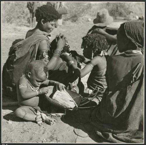 "Grooming & haircuts": //Khuana looking for lice on her child's head, N!ai looking for lice in the child's beads, and /Gaishay (son of Gao and Di!ai) examining a //guashi (print is a cropped image)