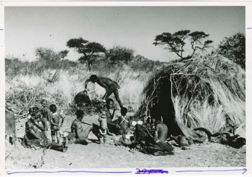 "Meat sharing": "Gao Medicine" bringing a quarter of meat in meat distribution to a group of people sitting in front of a skerm, including "Old ≠Toma" sitting in the middle of the group (print is a cropped image)