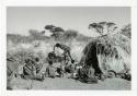 "Meat sharing": "Gao Medicine" bringing a quarter of meat in meat distribution to a group of people sitting in front of a skerm, including "Old ≠Toma" sitting in the middle of the group (print is a cropped image)