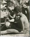 "Music": Two boys sitting, one playing a //guashi and one tuning one (print is a cropped image)