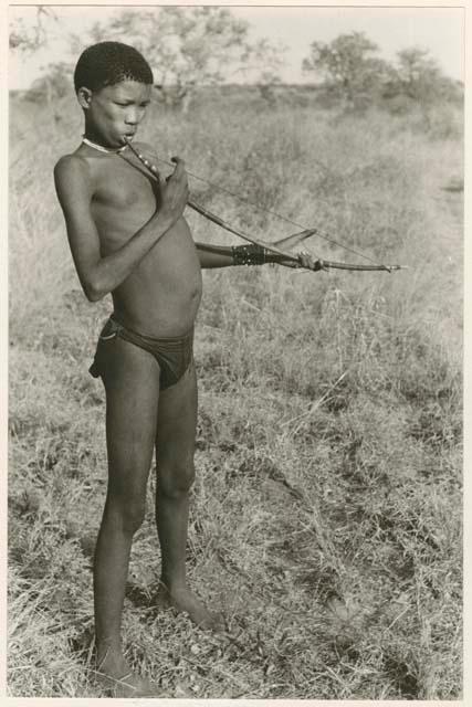 "Music": !Naishi (brother of /Goishay) playing a musical bow, with fingers, no sticks, end of bow in his mouth (print is a cropped image)