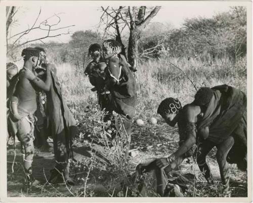 "Move": Group preparing to leave Gautscha for a hunting and gathering trip, including //Kushay (second wife of "Gao Helmet", headman of Band 2), Xama (Gao's daughter with his first wife) with bead ornaments in her hair, Khuan//a (daughter of "Old /Gaishay and Di//khao, //Kushay's sister) leaning over (print is a cropped image)