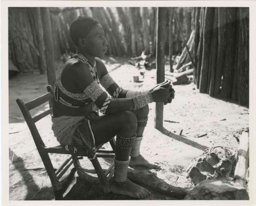 "Moremi's wife & a cow": Makiena (Muremi's wife) sitting in her kraal, wearing her Kwangali beads and copper anklets (print is a cropped image)