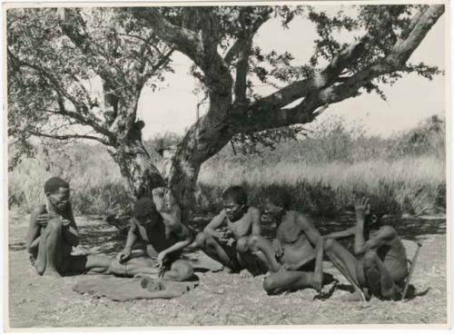 "Oracle disk": Man throwing oracle disks, and a group of men sitting and watching him (print is a cropped image)