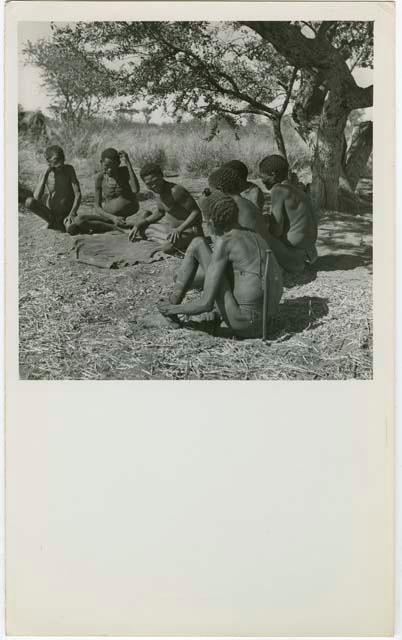 "Oracle disk": Man reading oracle disks, with a group of men sitting and watching him (print is a cropped image)