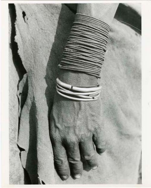 "Ornaments": Person's hand showing fiber bracelets and metal bracelets (print is a cropped image)