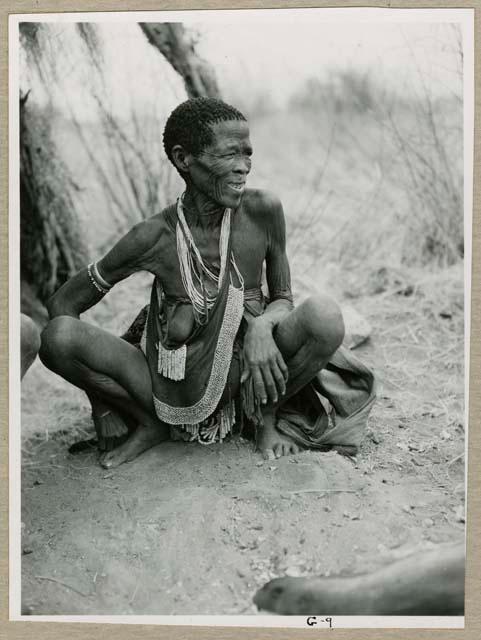 "Ornaments & beads": Di//khao (Gu!na) sitting, showing her beads and modesty apron (print is a cropped image)