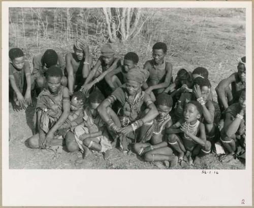 [No folder title]: Tsamgao, /Gunda, "≠Gao Lame" (headman of Band 1), unidentified man, ≠Gao (son of Gau), Gau (husband of Be and Khuan//a), and !Naishi (with headband) sitting in the back row; and ≠Nisa (wife of //Ao) with her baby, unidentified girl, unidentified woman (possibly from / /Ti!kay's group), unidentified child, "Little ≠Gao" (son of /Qui and //Kushay) and //Kushay (behind "Little ≠Gao") sitting in the front (print is a cropped image)