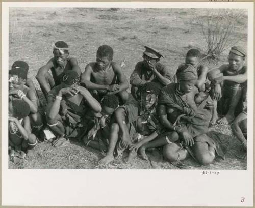 [No folder title]: !Naishi, "Old Gau" (father of //Kushay and !Ungka), and "≠Gao Helmet" sitting in back row; and !Naishi, and /Gasa (wife of /Qui) sitting in front row (print is a cropped image)