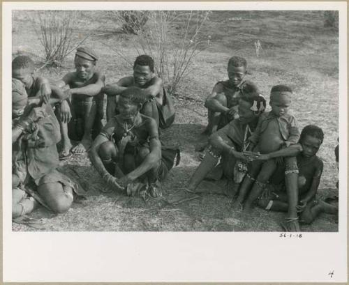 [No folder title]: /Qui, "/Qui Navel," and "Old ≠Toma" sitting in back row; /Gasa, unidentified woman (possibly !U's mother Naoka), Khuan//a (wife of Gau) with Qui (her son), and !Naishi (son of "/Qui Navel" and //Kushay) sitting in front row (print is a cropped image)