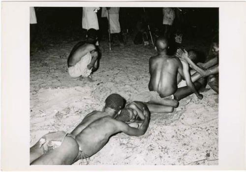 [No folder title]: Man lying on his stomach curing a sleeping boy, with two men aiding a man in trance behind them (print is a cropped image)