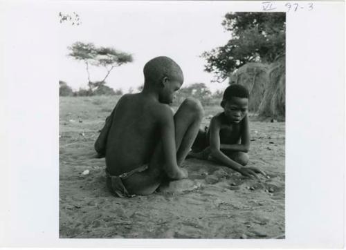 [No folder title]: Two boys playing /Ui (the counting game) in the sand (print is a cropped image)