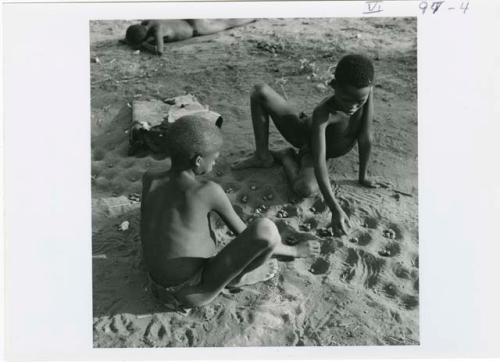 [No folder title]: Two boys playing /Ui (the counting game) in the sand, view from above (print is a cropped image)