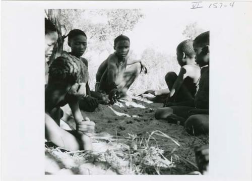 [No folder title]: Group of boys playing /Ui (the counting game) in the sand (print is a cropped image)