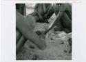 [No folder title]: Group of boys playing /Ui (the counting game) in the sand, close-up (print is a cropped image)