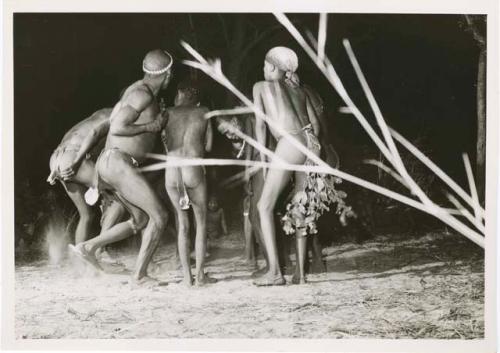 [No folder title]: Five men and boys dance with their backs to the camera in a night dance (print is a cropped image)