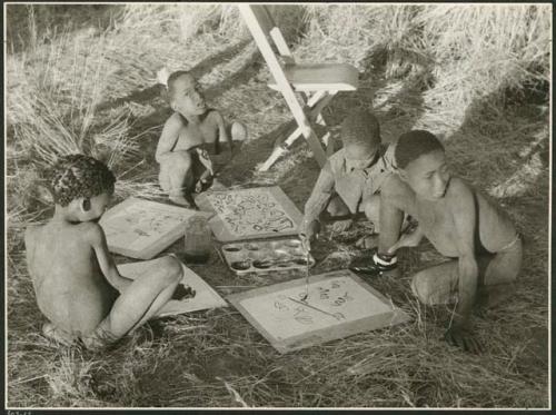 "Paintings, drawing and modelling": Four boys painting with Western materials, including /Gishay ("Old Gau's" son), with his foot bandaged, and Tsamgao (≠Toma's son), wearing a feather in his hair