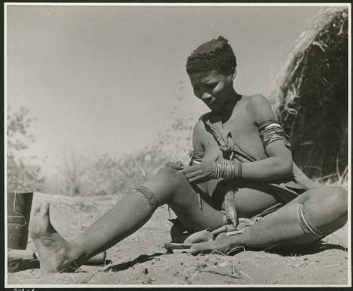 "Sewing": /Naoka sitting and working on beads (print is a cropped image)