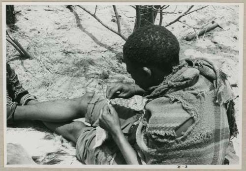 "Sewing": Tama, sitting on a rug, sewing (print is a cropped image)