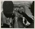 "Ornaments": Woman's hands fixing another woman's earring (print is a cropped image)