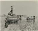 Group of people, including expedition staff members, around truck and John Marshall photographing from the top of it