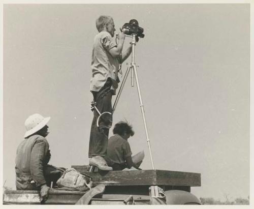 John Marshall filming from the top of the expedition truck, with Elizabeth Marshall Thomas and another expedition member sitting near him