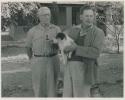 Frank and Bert Ramsden standing, with Bert holding their little dog