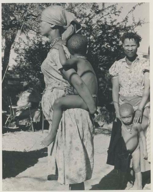 Woman wearing a dress and holding her child on her back