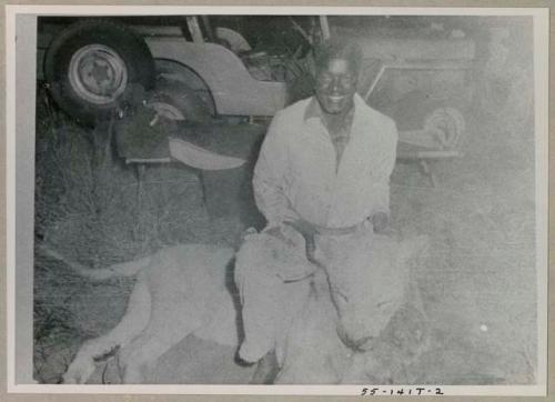 Simon Molamo sitting over a dead lion, holding the lion's head