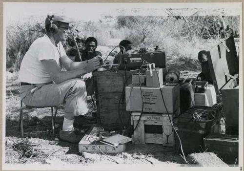 Men sitting next to Nicholas England using recording equipment
