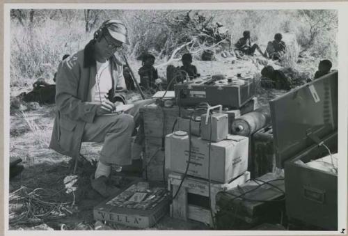 Nicholas England sitting at recording equipment and writing

