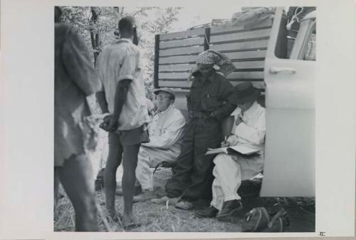 Man talking with Kernel Ledimo, Nicholas England and Lorna Marshall next to expedition truck

