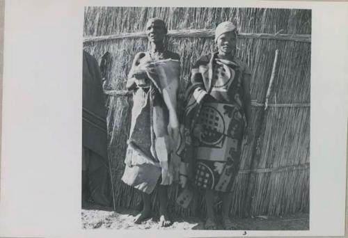 Two women standing in front of a fence

