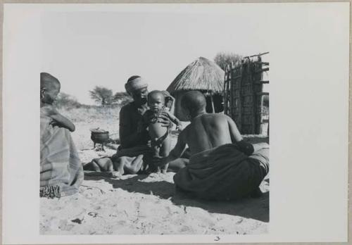 Three women sitting, one is holding a baby

